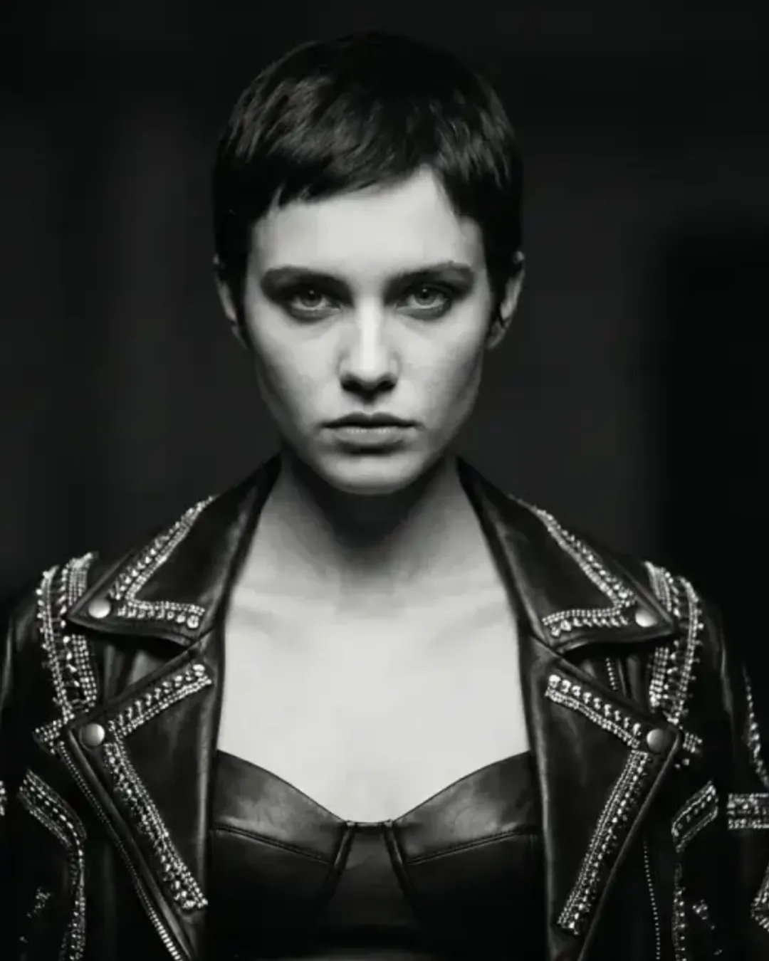 Black-and-white studio portrait of a woman with short hair in a studded leather jacket, an AI direction still by byTHELAB